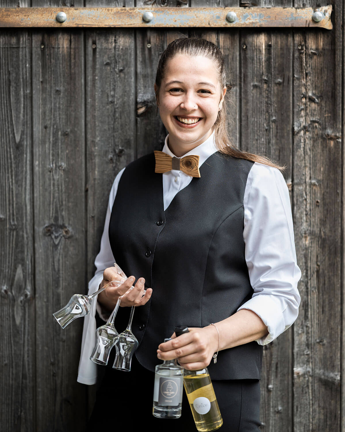 La padrona di casa Victoria tiene due bottiglie in una mano e tre bicchieri nell'altra - Naturhotel Miraval